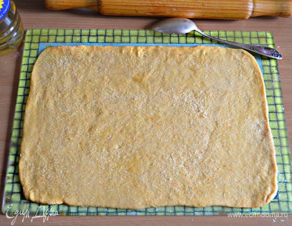 Раскатать тесто в прямоугольный пласт, смазать растительным маслом и посыпать сахаром (по 1 ст. л. с горкой на каждый пласт). 