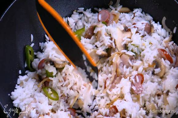 Добавить в вок готовый рис, влить соевый соус, соус чили и перемешать.