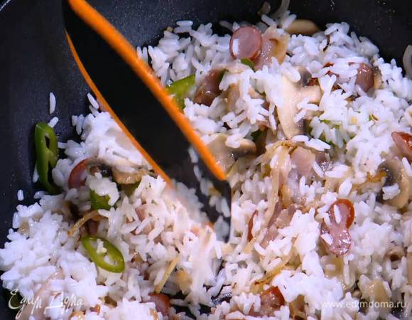 Добавить в вок готовый рис, влить соевый соус, соус чили и перемешать.