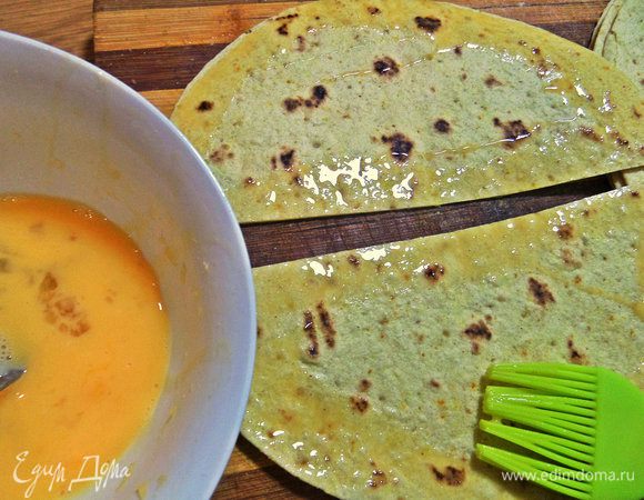 Возвращаемся к тортильям. Взбиваем яйцо и промазываем кисточкой края всех половинок лепёшек.