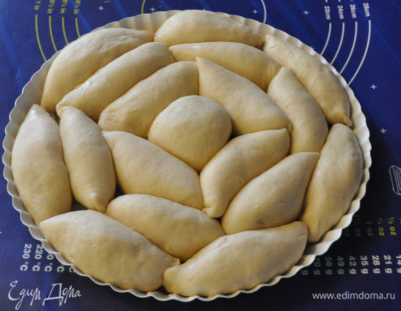 Форму для выпечки (у меня диаметром 28 см) смазать сливочным маслом и выложить пирожки швом вниз, чередуя пирожки с разными начинками. Накрыть форму с пирожками полотенцем и оставить подходить на 15-20 минут.
Включить разогреваться духовку до 180°C. 