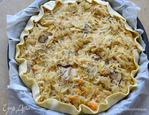 В форму для выпечки (у меня круглая, 28 см диаметром, но можно взять и прямоугольную) выложить пласт слоеного теста (у меня готовое). Наколоть тесто вилкой и выложить сверху начинку, разровнять.