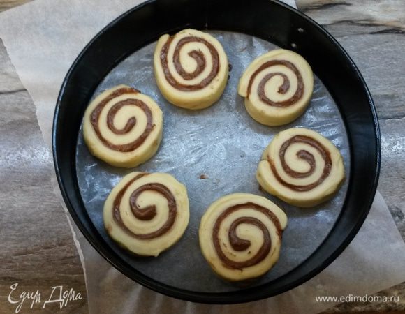 На дно разъемной формы диаметром 26-28 см кладем пергамент. Форму смазываем сливочным маслом. Выкладываем булочки, накрываем полотенцем, оставляем при комнатной температуре на 1.5 часа.