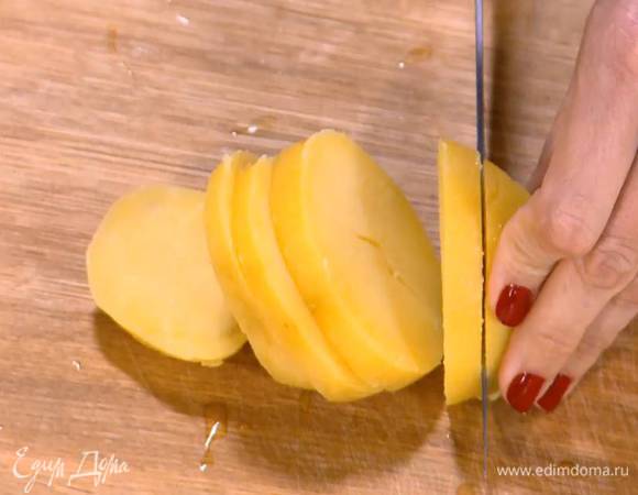 Картофель отварить в мундире, затем почистить и нарезать толстыми ломтиками поперек.