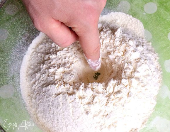 Придав муке вид горы с ямкой в центре.