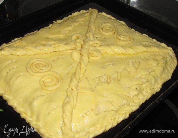 Смазать пирог слегка взбитым яйцом или жидкой сметаной при помощи кулинарной кисти. Нанести элементы декора, их тоже смазать яйцом. Пирог проткнуть вилкой в нескольких местах для выхода пара.