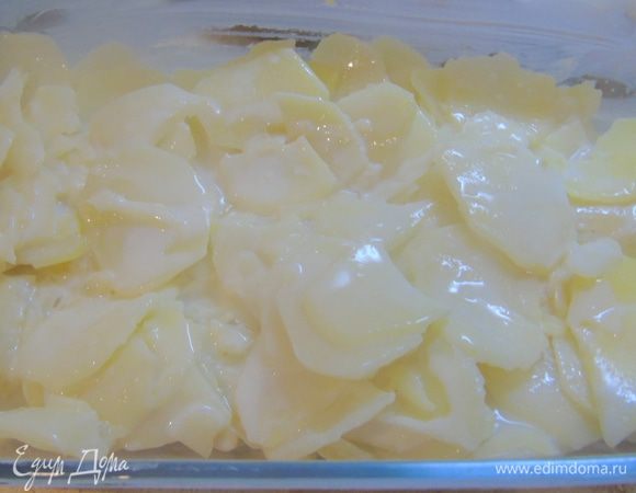Форму для запекания смазываем сливочным маслом, шумовкой выкладываем половину картофеля.