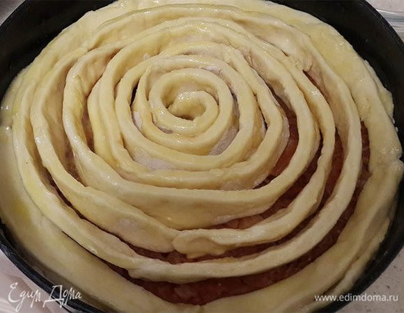 Выложить начинку. Украсить оставшимся тестом. Для этого раскатать тесто и нарезать на полоски. Скрутить, начиная от центра, по спирали. Смазать желтком с сахаром, взбитыми вилкой. Выпекать около 45-50 минут.