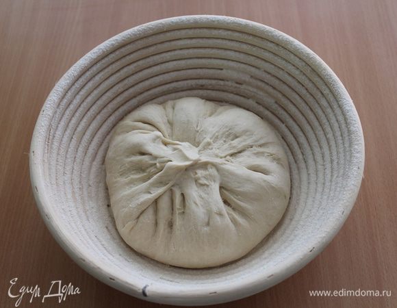 Выброженное тесто  выложите на подпыленную мукой поверхность. сформируйте круглый хлеб, защипните шов в центре. Уложите заготовку в расстоечную корзину швом кверху или на пергамент для выпечки швом вниз.