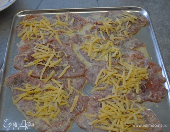 Далее обмакиваем каждую отбивную в получившийся соус и выкладываем на смазанный маслом противень. Сверху посыпаем тертым сыром и отправляем в, разогретую до 200 градусов, духовку на 30 минут.