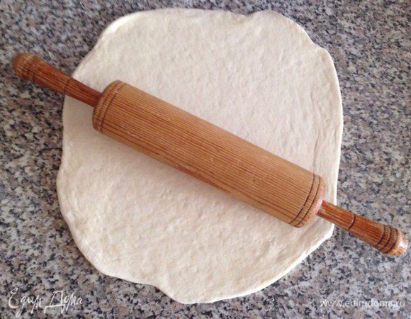 Раскатываем тесто (я люблю делать круглую форму). Чтобы тесто не прилипало к рабочей поверхности то лучше присыпать ее немного мукой (лишнее потом стряхнуть). Выложить на противень, накрыть кухонным полотенцем и дать настояться минут 15-30. Затем еще раз распределить его по противню (тесто немного могло приподняться пока настаивалось, поэтому для тех, кто любит тонкое тесто то его надо подраскатать еще немного. Включаем духовку на 180-200°С.