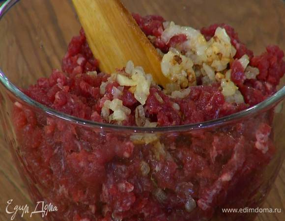 Обжаренный лук с чесноком немного остудить, затем выложить в фарш, посолить, поперчить, влить 100 мл ледяной воды, перемешать, добавить 1 ч. ложку предварительно размягченного сливочного масла и все вымешать.