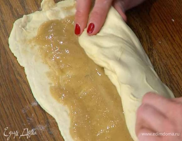 На тесто, отступив на пару сантиметров от края, равномерно выложить начинку, затем скатать в рулет и свернуть улиткой.