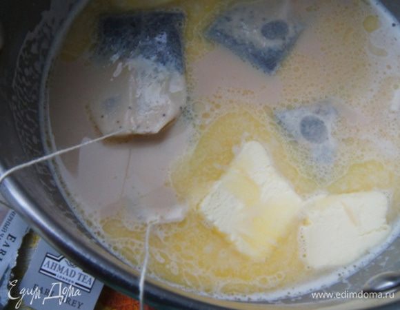 Молоко вскипятить. Положить в него пакетики чая и масло. Накрыть крышкой  и оставить, чтобы чай заварился и масло растопилось. 
