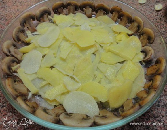 Картофель нарезать как можно тоньше. У меня с этим отлично справляется терка. Часть картофеля выложить на дно формы. Его можно не солить, ведь сверху будут грибы.