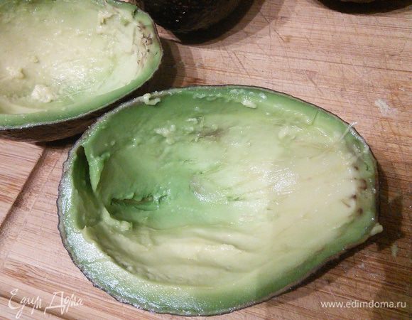 Авокадо вымыть, обсушить, разрезать наполовину, извлечь косточку. Авокадо должен быть спелым. Ложкой вынуть до 2/3 мякоти. Мякоть нарезать и аккуратно вмешать в остальной салат.