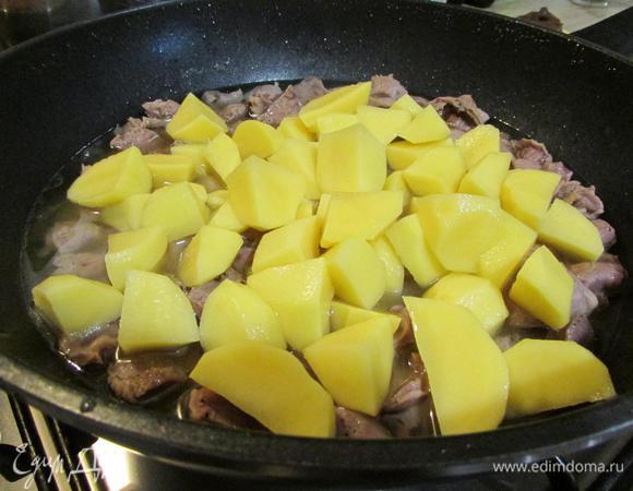 Через 1,5 часа к желудкам добавить картофель. Закрыть сковороду крышкой и тушить до готовности картофеля.