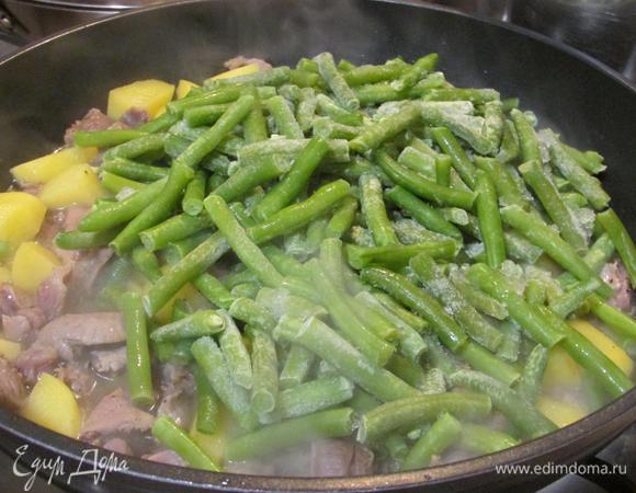 В сковороду добавить стручковую фасоль, снова закрыть крышкой и тушить еще 5 минут.