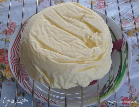 На следующий день достаем торт, освобождаем от формы и переворачиваем. Выкладываем на решетку, под которой будет посудина для стекания глазури. У меня из-за пленки совсем неровный тортик, но глазурь все сгладит.