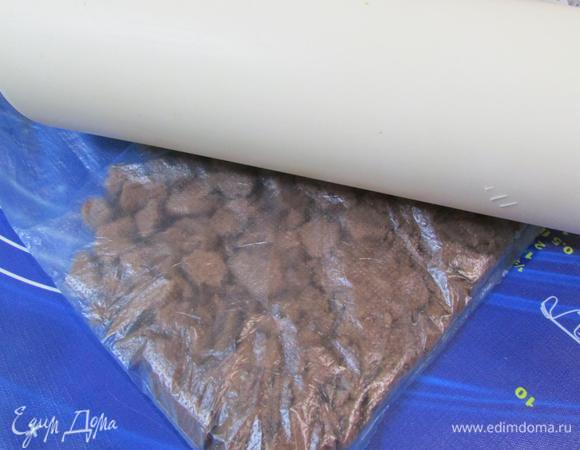 Шоколадное печенье выложить в целлофановый мешок и измельчить в крошку с помощью скалки.