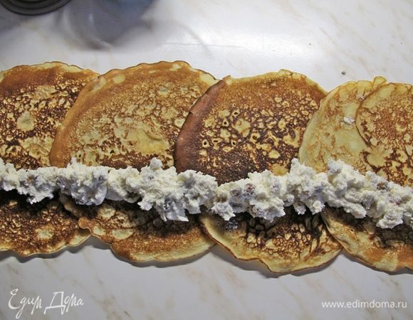 Если форма у вас не силиконовая, на дно кладем лист бумаги для запекания.
Блинчики кладем внахлест, сверху начинку и сворачиваем рулетиком. 