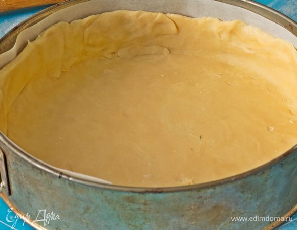 Через 30 минут достать тесто из холодильника, раскатать. Форму застелить бумагой для выпечки. Тесто выложить в форму, сформировать бортики высотой 3 см, наколоть вилкой и снова убрать в холод.