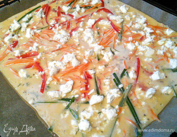 Вынуть противень и выстрелить его бумагой для выпечки, предварительно смазанной маслом. Вылить тесто на противень, разложить овощи и фету. Запекать 15 минут. 
