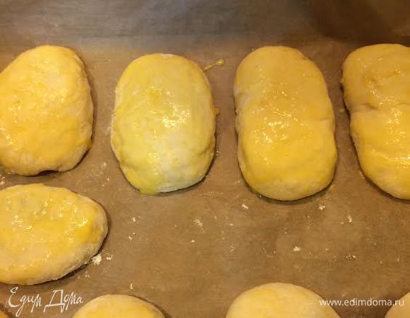 Противень застелить бумагой для выпечки. Выложить пирожки. Смешать 1 желток и 2 ст.л молока и смазать пирожки. Дать пирожкам подняться (10 минут).