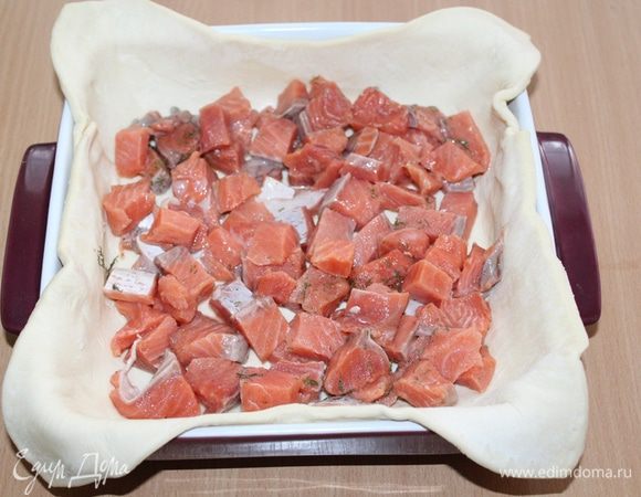 Выложить тесто в форму, затем кусочки рыбы.