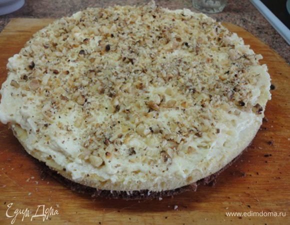 Накрываем светлым коржом, смазываем кремом и посыпаем второй половиной орехов.