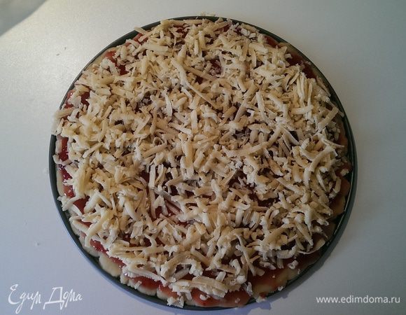 Достаем большой шарик и раскатываем. ( размер раскатанного блина соответствует форме для выпекания). Затем смазываем блин вареньем.
После этого достаем маленький шарик и трем его на тёрке и посыпаем основу.