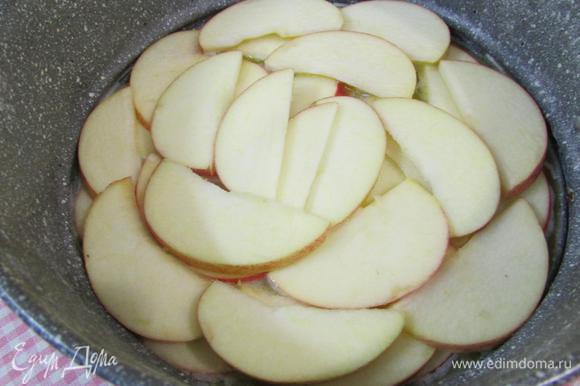 В масло выложить яблоки, нарезанные пластинами.