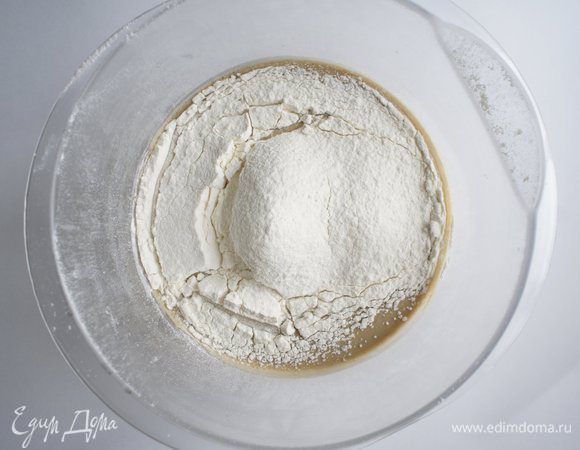 Постепенно, небольшими порциями добавить просеянную муку, постоянно перемешивая венчиком, избавляясь от комочков.