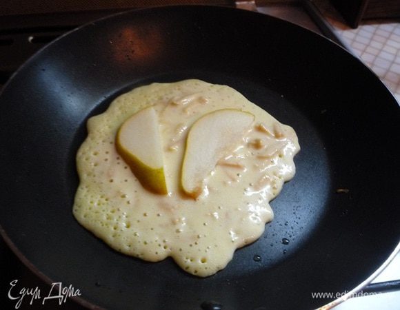 В сковороде разогреваем немного растительного масла. Выкладываем тесто ложкой. Когда блины схватятся снизу, выкладываем на них дольки груши и переворачиваем на другую сторону.
Обжариваем до румяного цвета 1-2 минуты.