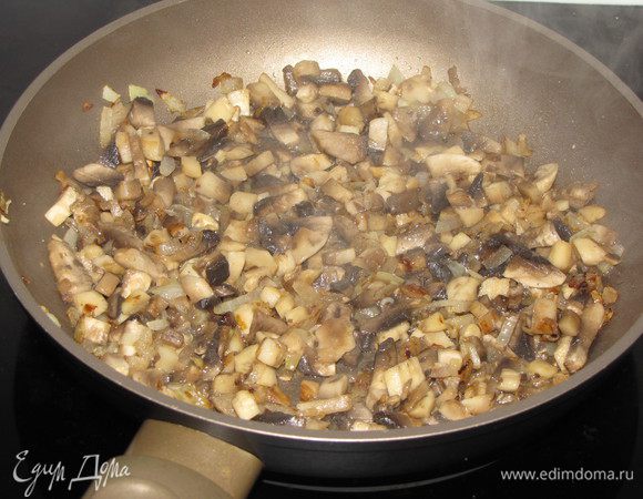 Разогрейте в сковороде растительное масло и обжарьте мелко нарезанный репчатый лук, затем добавьте нарезанные мелким кубиком шампиньоны. Шампиньоны желательно взять крупные. Жарьте еще минут 5, помешивая.