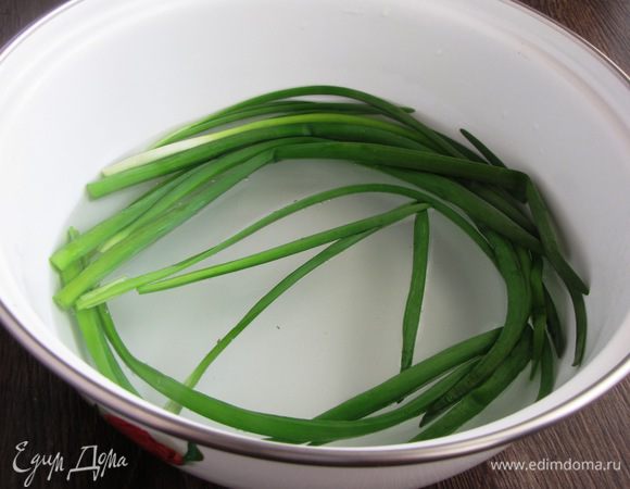 От зеленого лука отрежьте белую часть, выберите хорошие перышки. Положите их в миску и залейте кипятком на несколько секунд. Это нужно для того, чтобы лук не рвался при завязывании.