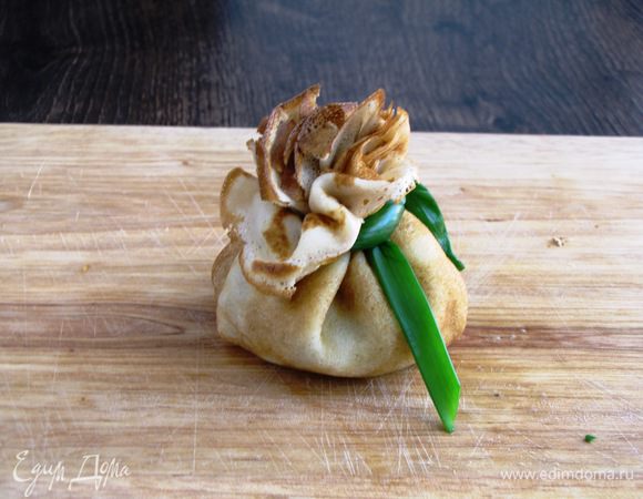 Соберите края блинчика вокруг начинки, образуя складки, и завяжите перышком зеленого лука. Торба готова.