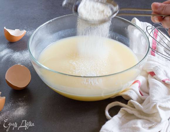 Постепенно, небольшими порциями, высыпьте просеянную муку, постоянно и тщательно перемешивая. 
