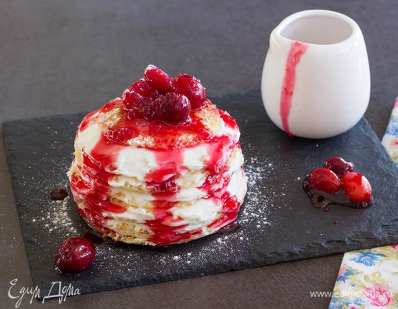 Соберите торт. Положите один блин и смажьте кремом. Накройте вторым блином, намажьте кремом, и так все блинчики. Полейте десерт ягодным соусом и посыпьте сахарной пудрой. Приятного аппетита! 