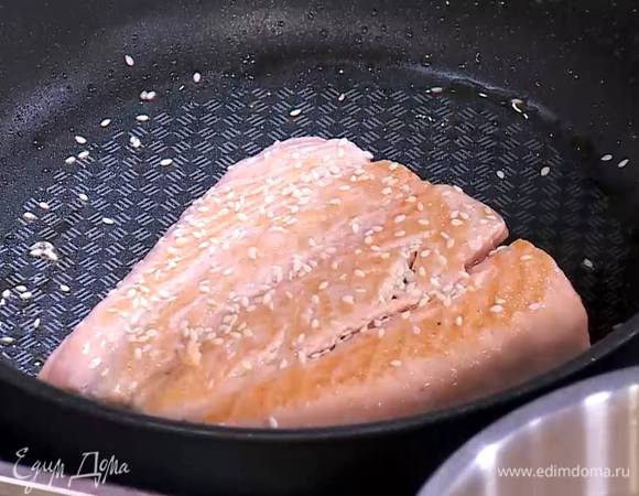 Разогреть в сковороде немного кунжутного масла, выложить семгу кожей вниз, сбрызнуть кунжутным маслом и прогревать на среднем огне, пока рыба снизу не посветлеет, затем перевернуть ее, посыпать щепоткой кунжута и жарить до готовности.