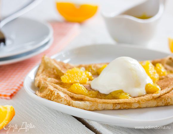 Готовые блины выложите на тарелку в центр положите фламбированные апельсины и сверните края блинов с двух сторон на начинку, сверху выложите шарик ванильного мороженого и полейте соусом.