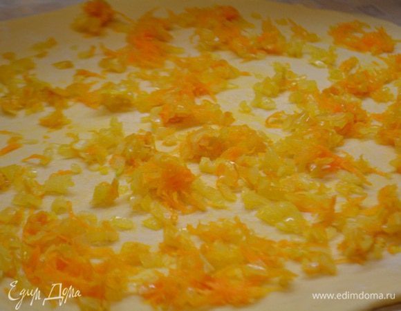 Пока тесто вымешивается сделаем зажарку из овощей. Чистим лук и морковь. Лук нарезать полукольцами,морковь потереть на крупной терке. Обжарить на раскаленной сковороде с добавлением постного масла до мягкости. Остудить. Раскатать тесто в тонкий пласт, разложить по всей поверхности теста овощи.