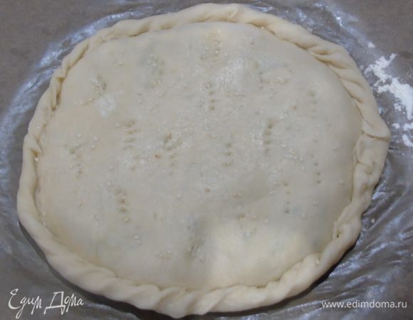 Раскатываем вторую часть теста и накрываем, края заворачиваем, так формируем две лепешки, делаем вилкой дырочки, присыпаем кунжутом и отправляем в разогретую до 170°C духовку на 35-40 минут, до золотистости.