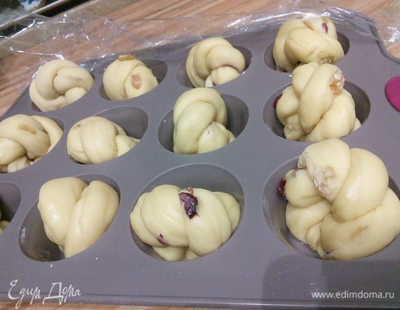 Форму для маффинов щедро смазать маслом. Заготовки поместить в формочки кончиками косичек внутрь. Притрусить мукой, накрыть пленкой и поставить в холодильник на ночь (10-12 часов). 

