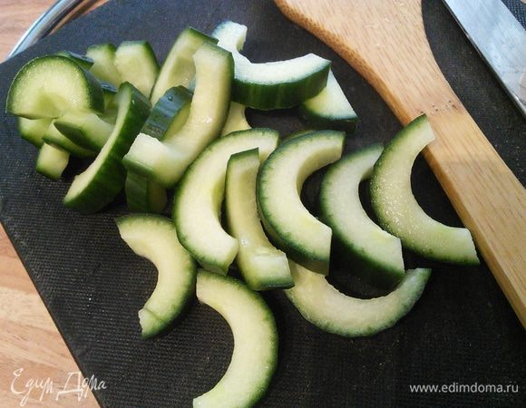 Вмешать лапшу в соус. Огурец порезать вдоль на две половины, вынуть семена и нарезать на шайбы. 