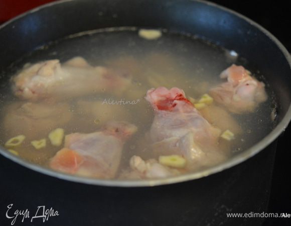 Разогреть духовку до 220°C.
Противни застелить пищевой фольгой.
В большой кастрюле вскипятить воду. Добавить очищенный и тонко нарезанный чеснок, куриные крылышки (у меня основная часть крыла).  Кипятить на медленном огне примерно 8 мин.