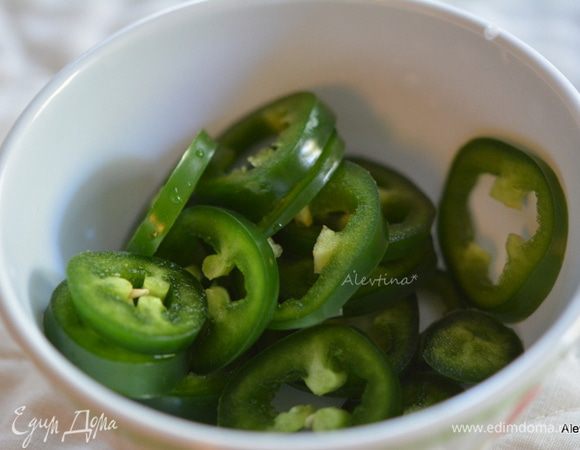 Выложить крылышки в большое блюдо. Полить соусом и перемешать. Халапеньо нарезать колечками. 