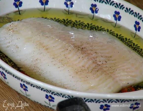 На дно жаропрочной керамической формы выложить перец чили, чеснок, посыпать розмарином, посолить, поперчить, сверху уложить палтус и залить все горячим оливковым маслом, так чтобы филе было покрыто.