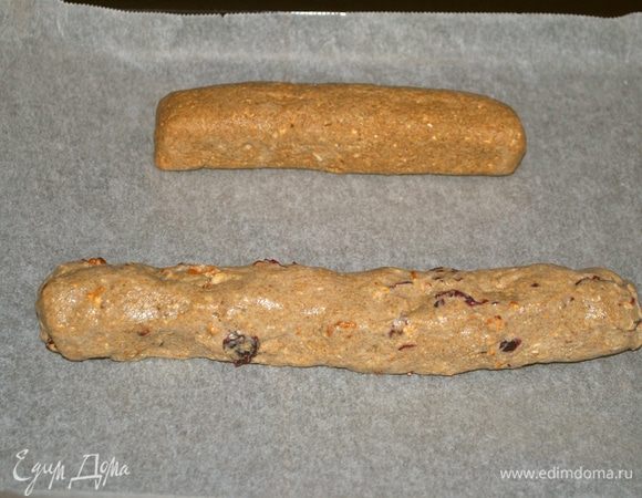 Затем я делю полученное тесто на 2 равные части. Из одной части, мокрыми руками на мокрой рабочей поверхности формирую батончик. Во вторую часть добавляю орехи и вишню. Хочу сразу сказать, что вишня у меня домашняя сушеная, а не вяленая, т.к. нет такого ингредиента в списке. Тоже формирую батончик. Включаю духовку на 180°C. После того как духовка нагрелась отправляю туда противень на 20 мин.
