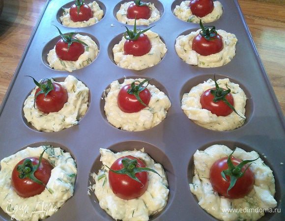 В формы для маффинов положить бумагу для выпечки. Наполнить тестом и в каждую поместить по помидорке. Помидорки должны быть в идеале с "хвостиком".